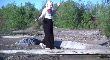 Leggy blonde Nura sits down for a piss on driftwood at the beach