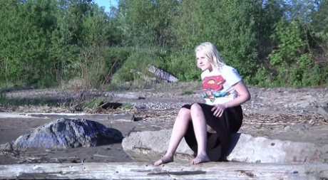 Leggy blonde Nura sits down for a piss on driftwood at the beach