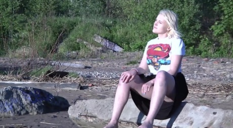 Leggy blonde Nura sits down for a piss on driftwood at the beach