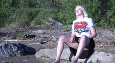 Leggy blonde Nura sits down for a piss on driftwood at the beach