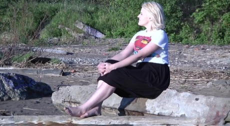 Leggy blonde Nura sits down for a piss on driftwood at the beach