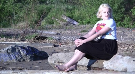 Leggy blonde Nura sits down for a piss on driftwood at the beach